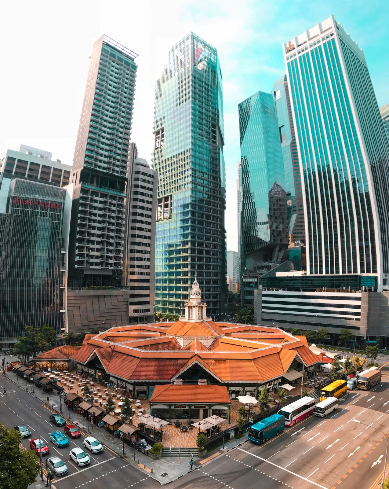 A low market hall sitting among taller city towers, still in use at street level